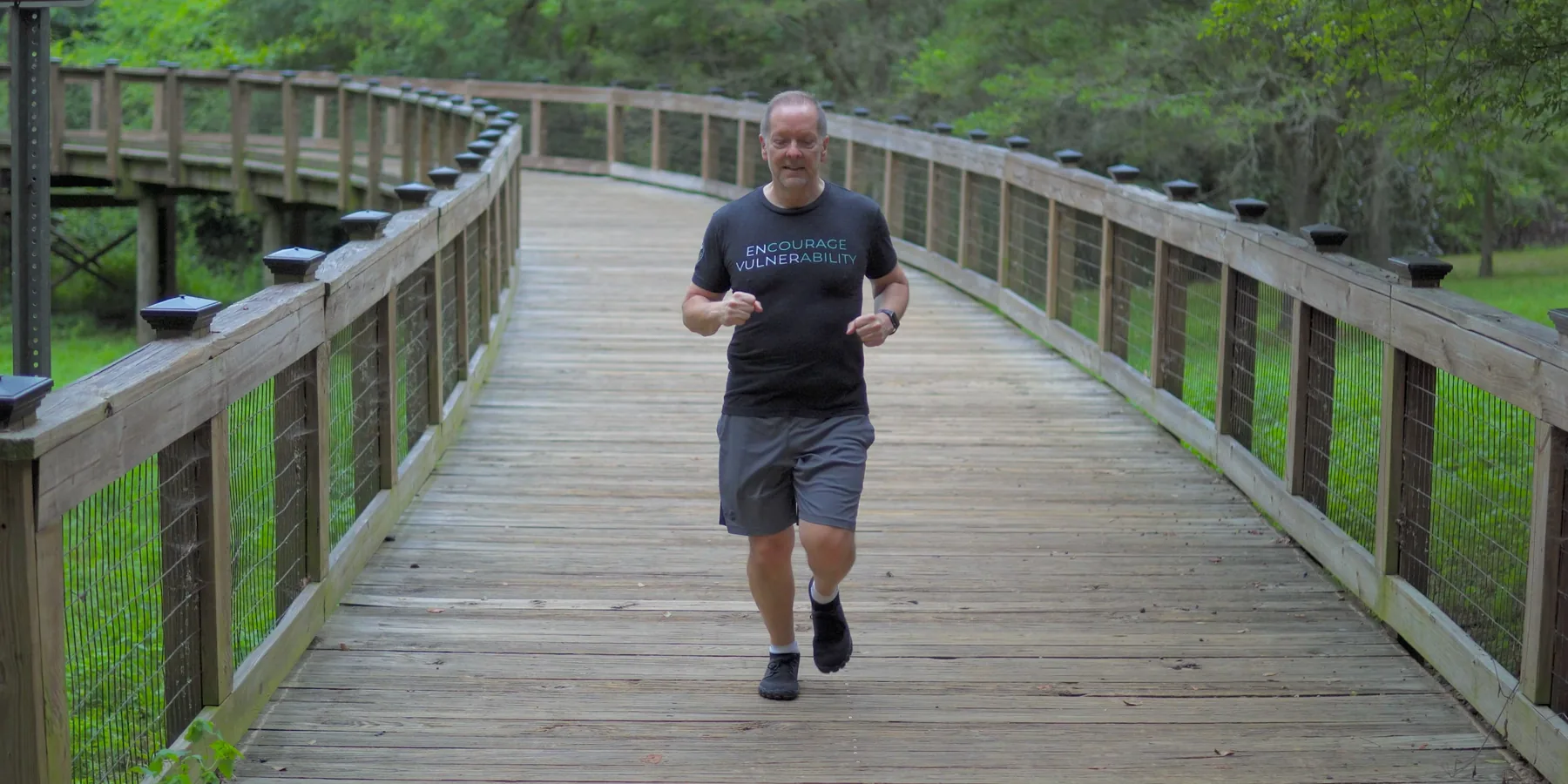 A man running at a steady pace on a flat path